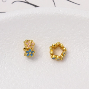 Primer plano de cuentas florales doradas con esmalte rosa y azul para joyería artesanal