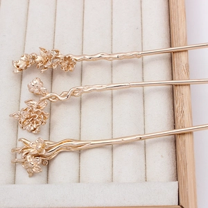 Macro detail of three golden floral hairpins with plum blossom design and branch textures