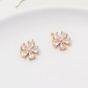 Macro shot of two gold-plated daisy flower pendants with clear zircon petals and jump rings