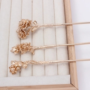 Detailed close-up of golden metal floral hairpins with intricate peony and lotus designs