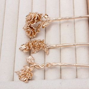 Detailed view of three golden flower hairpins with intricate embossed floral textures