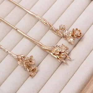 Macro shot of three golden floral hairpins with lotus and lily motifs for Hanfu