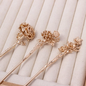 Detailed view of three vintage gold floral hairpins with intricate traditional carvings