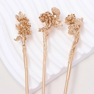 Detailed macro of three gold-plated copper hair pins with intricate floral textures