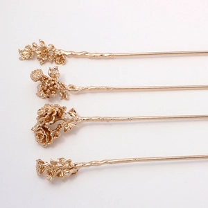 Detailed close-up of four vintage gold copper flower hairpins with intricate floral textures