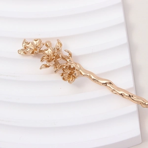 Detailed close-up of golden metal flower hair pin with branch texture and matte finish