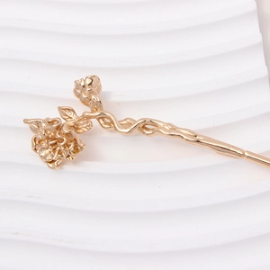 Detailed macro view of a golden rose flower hair pin with realistic metal petals and leaves