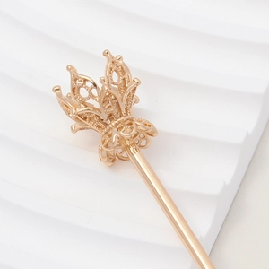 Detailed macro shot of a golden hollow crown hairpin accessory with intricate metal textures