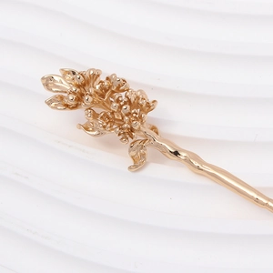 Close-up of golden copper flower hair stick with intricate botanical branch details