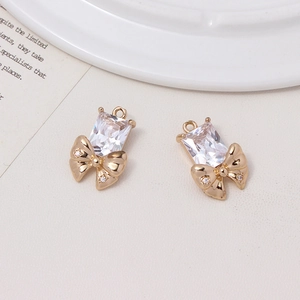 Macro shot of gold bow-shaped charms with large clear zircon for DIY jewelry making