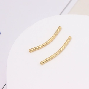 Makroaufnahme von 18K vergoldeten S-förmigen gebogenen Perlen mit diamantgeschliffener Textur