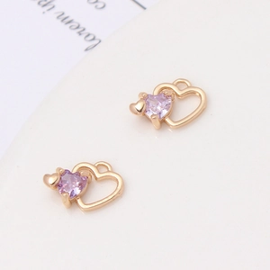 Macro view of gold copper heart pendants with purple zircon inlays for DIY jewelry