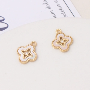 Detailed close-up of golden clover charms featuring white shell inlay and zircon accents