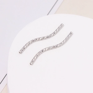 Makro-Detail von silbernen S-förmig facettierten Metallröhren für DIY-Schmuckherstellung