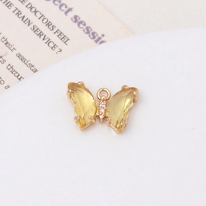 Vue macro d'un pendentif papillon doré avec zircons jaunes sur fond blanc pur