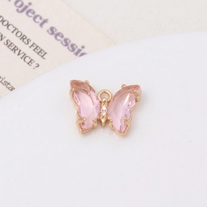 Vue macro d'un pendentif papillon en cristal rose avec cadre doré sur support blanc
