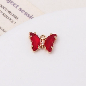 Détail de petit pendentif papillon doré avec cristaux rouges et zircons blancs