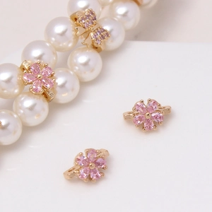 Macro shot of gold-plated flower and bow spacers with pink zircon for DIY jewelry