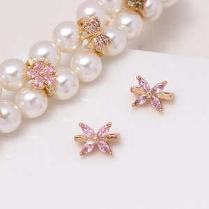 Detailed macro view of gold-plated flower and bow spacers with pink zircon for DIY jewelry