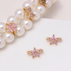 Macro shot of gold-plated flower and butterfly zircon spacer beads on a pearl necklace
