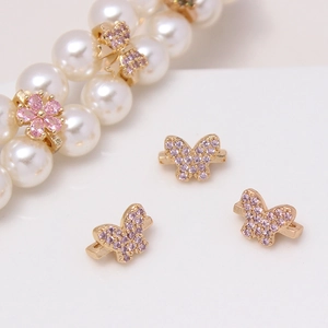 Macro shot of gold floral and butterfly spacer beads with pink pavé zircon for DIY jewelry