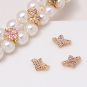 Macro detail of micro-paved zircon flower and clover spacers for DIY pearl jewelry