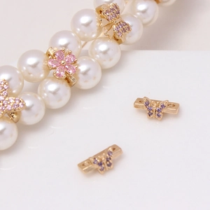 Macro detail of gold flower and butterfly spacers with micro-set zircons for pearl jewelry