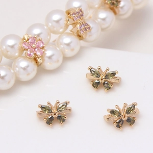 Macro detail of gold plated flower and butterfly charms with micro-pave zircons for DIY jewelry