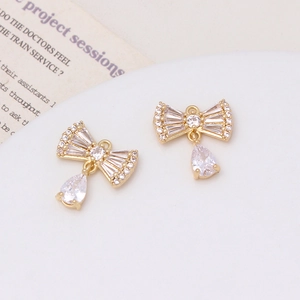 Macro view of 18K gold-plated bow pendants featuring micro-pave zircons for DIY jewelry