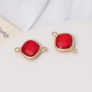 Détail de pendentifs en verre facetté rouge avec cadres dorés pour création bijoux DIY