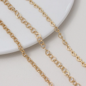 Vue macro de diverses chaînes dorées avec maillons en cœur et ronds pour la création de bijoux