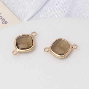Vue macro de breloques en cristal brun fumé avec monture dorée et doubles anneaux de fixage