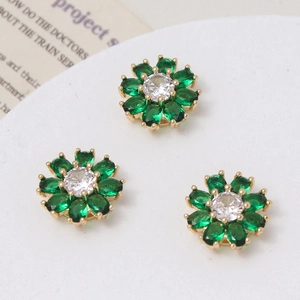 Macro detail of three gold-plated daisy charms with green crystal petals and zircon centers