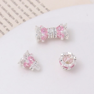 Pink heart-shaped jewelry clasp with zircon and silver base on a ceramic tray