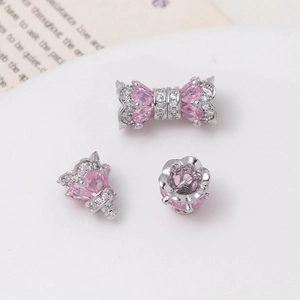 Macro shot of silver bow bead and crown spacers with pink drop zircon for jewelry DIY