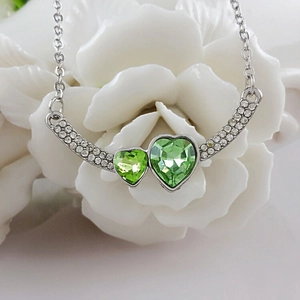 Collana d'argento con cristalli a cuore verdi e zirconi su fiore di camelia bianca
