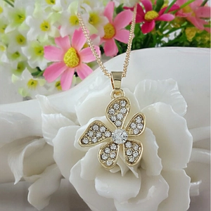Elegante collana a fiore dorata con petali di cristallo su ceramica bianca d'arte
