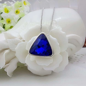 Macro view of a triangular navy blue crystal pendant with a sleek silver chain