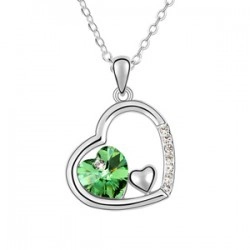 Détail macro du collier pendentif cœur en cristal vert et cadre en argent avec zircone