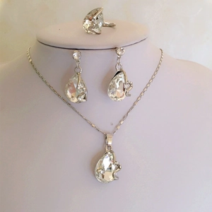 Detail van druppelvormige kristallen sieradenset met ketting oorbellen en ring op buste