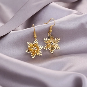 Detailansicht goldener Schneeflocken-Ohrringe mit Kristall-Strass auf Seidenstoff