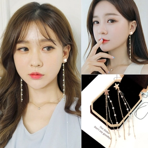 Élégantes boucles d'oreilles étoile dorée avec pompons et perles sur modèle