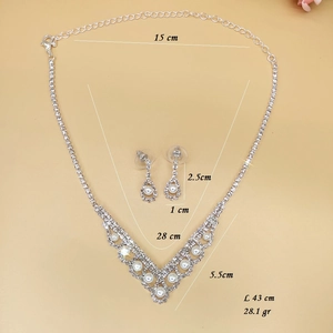 V-shaped necklace set with sparkling rhinestones and white pearls on beige background