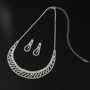 Detailed view of silver bridal rhinestone necklace and matching earrings on black background