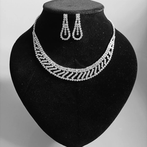 Elegant silver bridal jewelry set with rhinestone necklace and teardrop earrings on a black bust