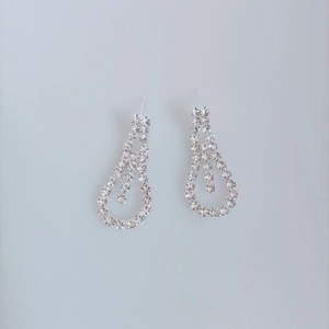 Close-up of silver-tone teardrop bridal earrings with intricate crystal pavé details