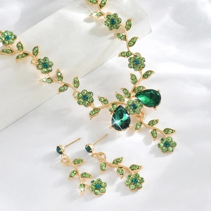 Detailed close-up of emerald green floral jewelry set with golden vine design