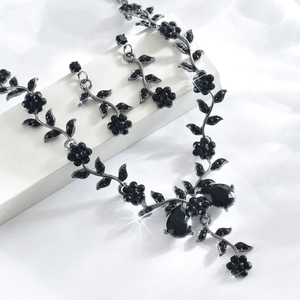Gros plan sur l'ensemble bijoux fleurs noires avec cristaux et pierres en goutte