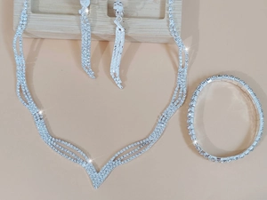 Dettaglio macro della collana a V argento e orecchini pendenti con nappine di strass