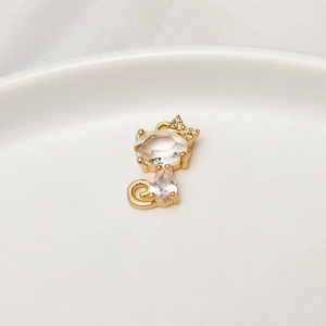 Macro di ciondolo a gatto dorato con zirconi a goccia su un piatto in ceramica bianca